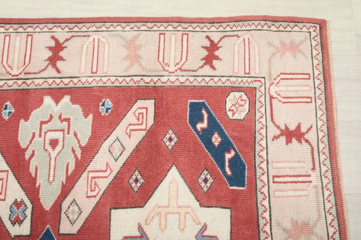 Detailed view of the upper right corner of the rug, highlighting the beige border and red field motifs.