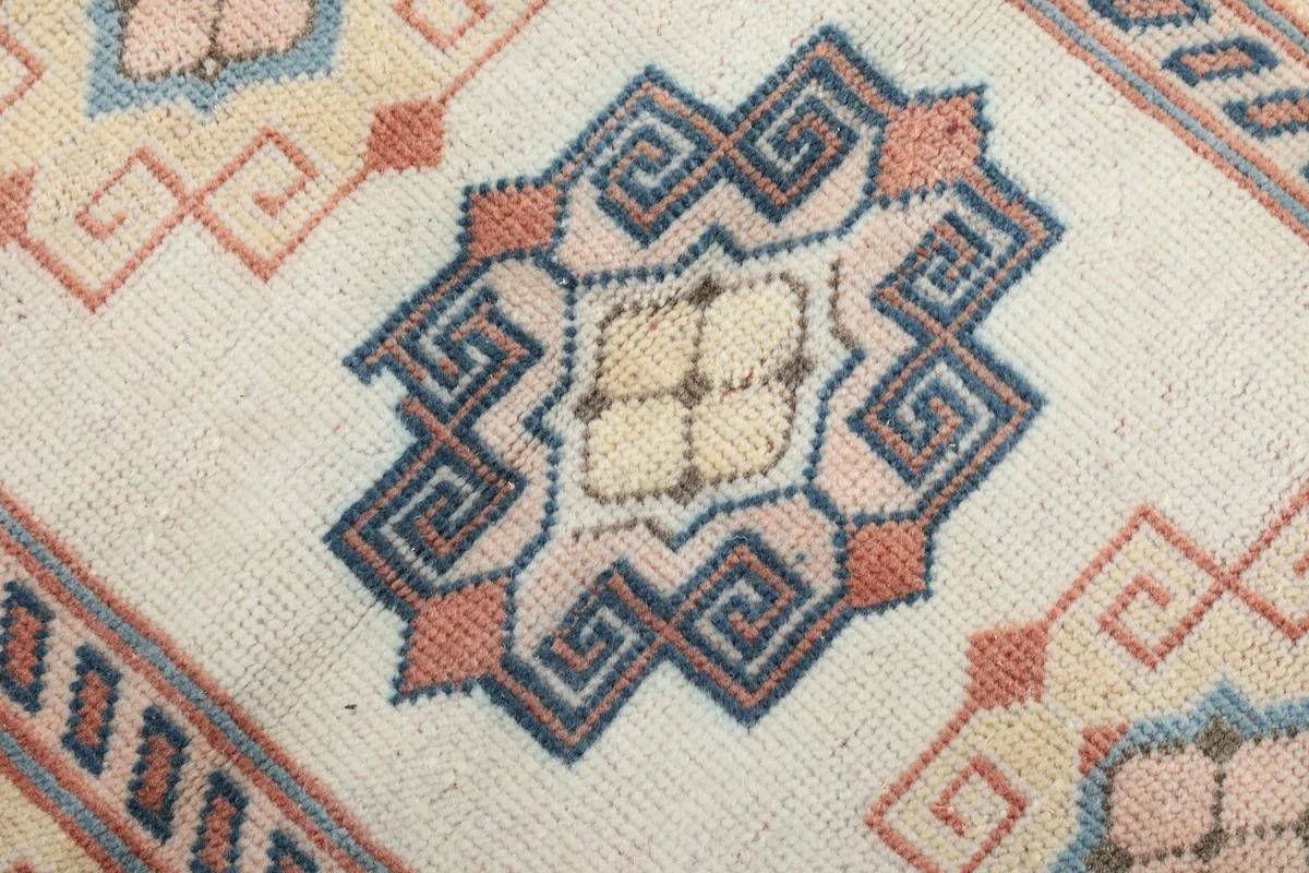 Detailed view of the central blue and pink geometric motif within the medallion