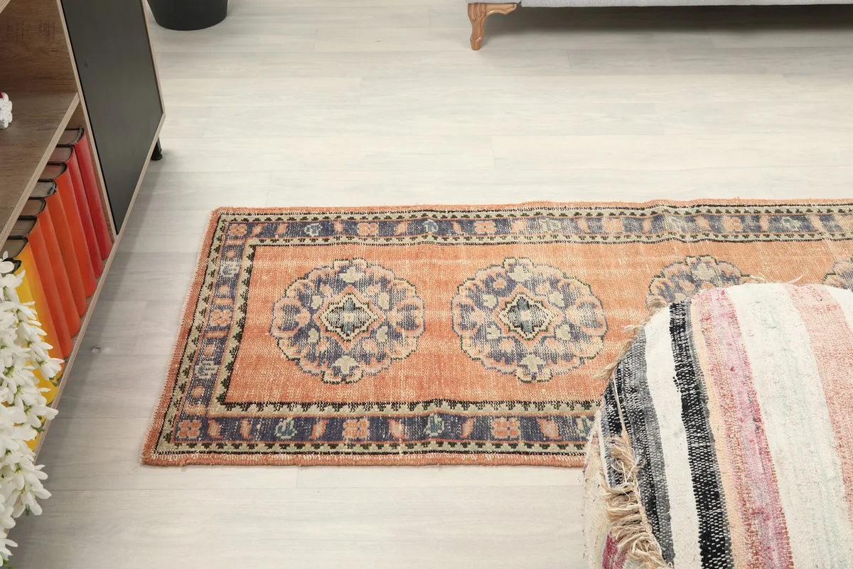 Angled view of the rug from above, showing a section of the medallions and border in a room
