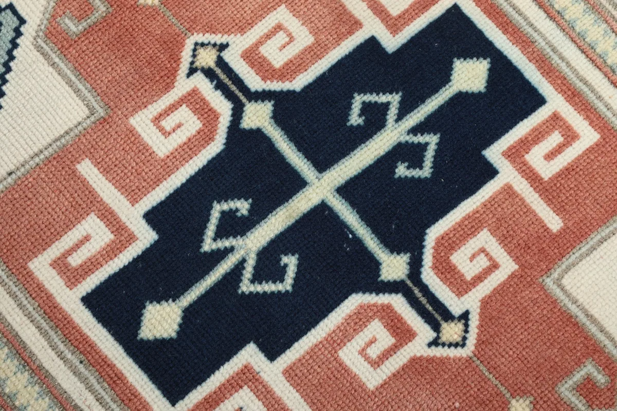 Close-up of a single navy geometric motif, showing the intricate hand-knotted wool pile texture.