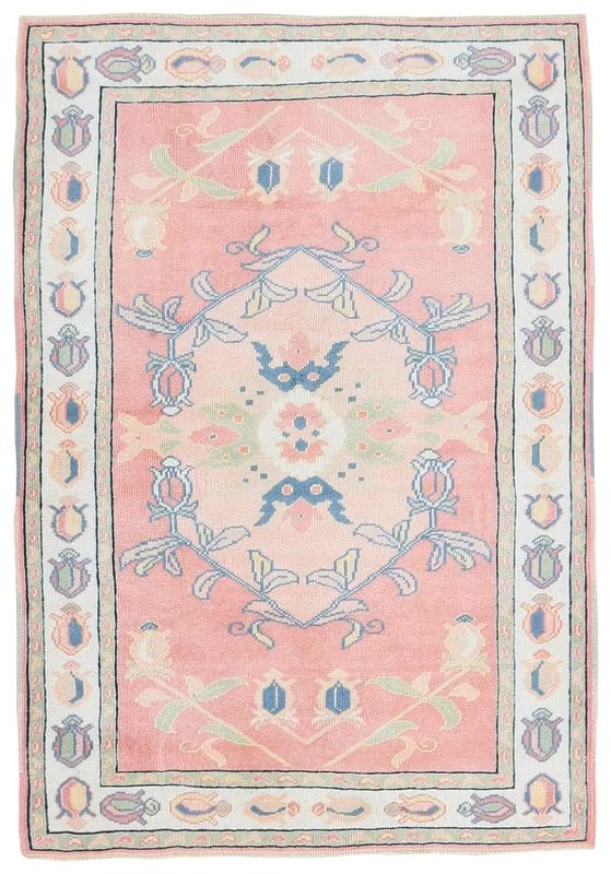 Full overhead view of the pink vintage Anatolian rug with a central floral medallion on a white background