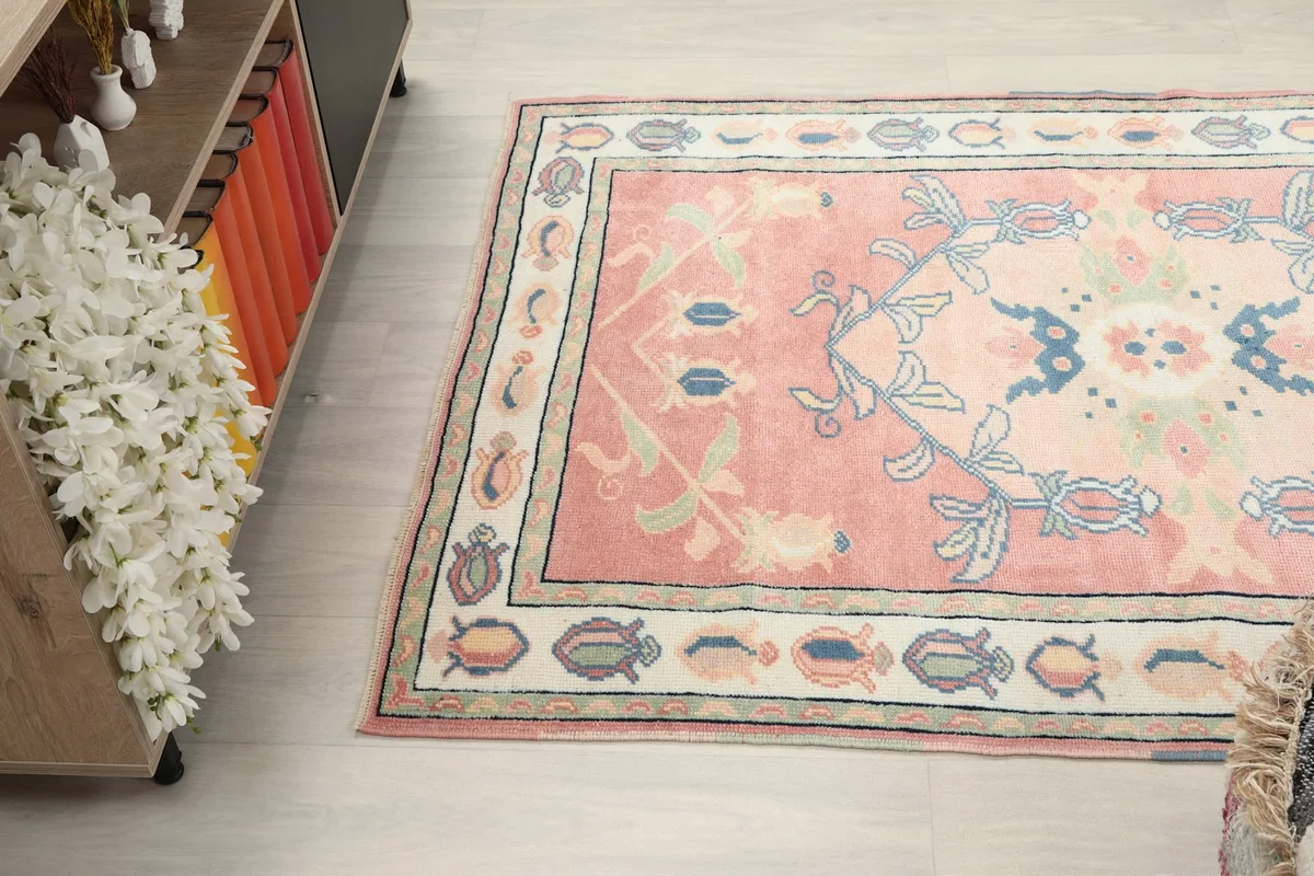 Wide-angle view of the pink rug in a room, showing its full length and the surrounding decor