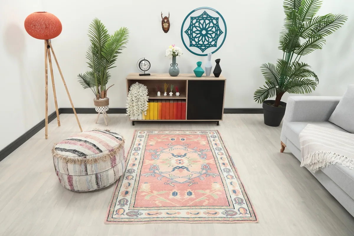 Vintage pink rug placed in a modern living room setting with a sofa and ottoman