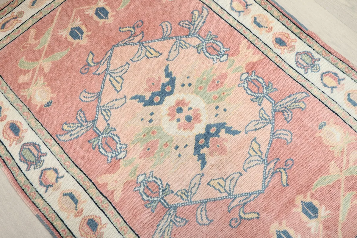 Overhead close-up of the central floral medallion and surrounding designs on the pink field