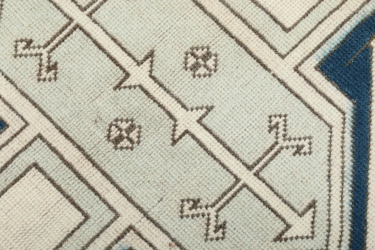 Extreme close-up showing the low wool pile and intricate knotting of the rug