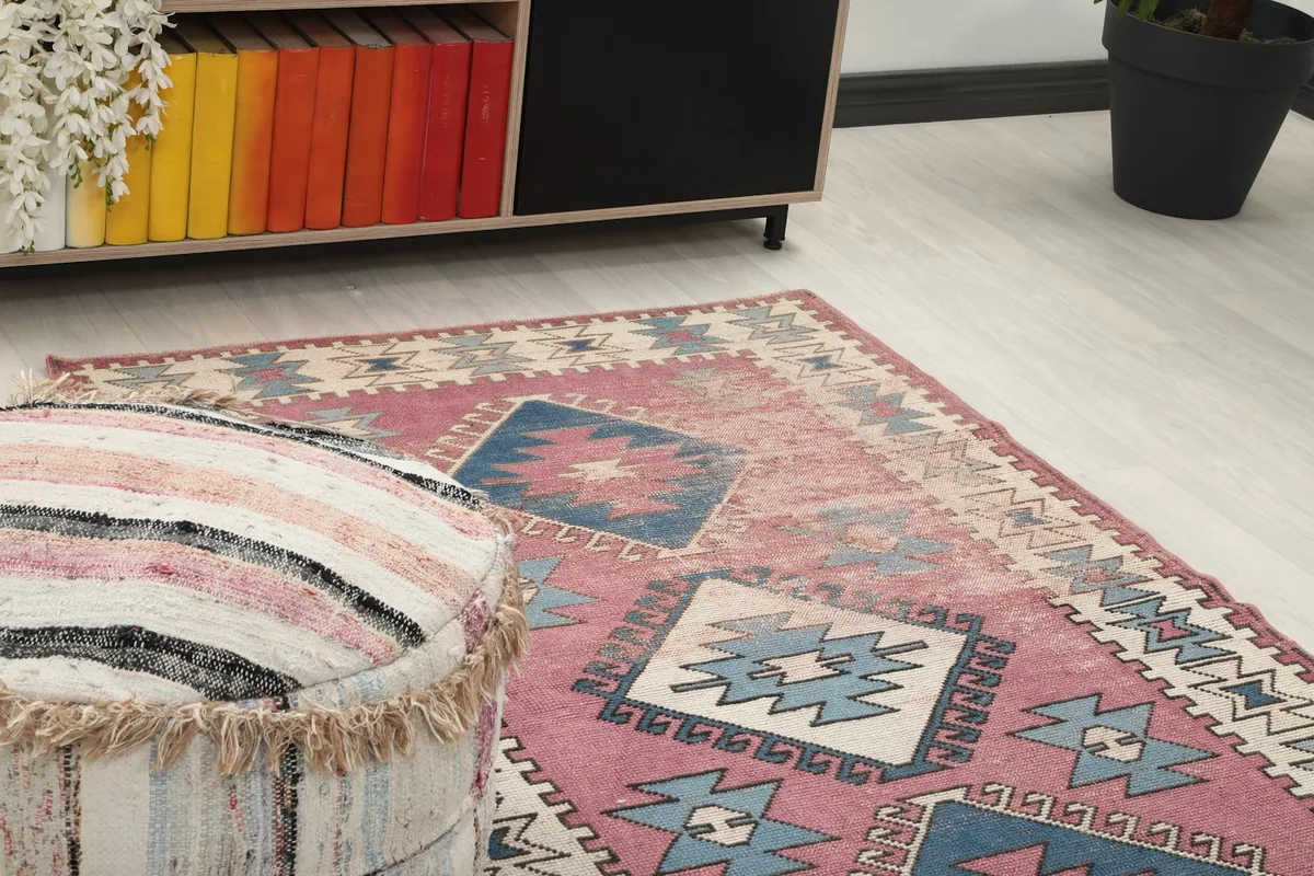 Close-up angle view of the rug's patterns and colors next to a striped ottoman