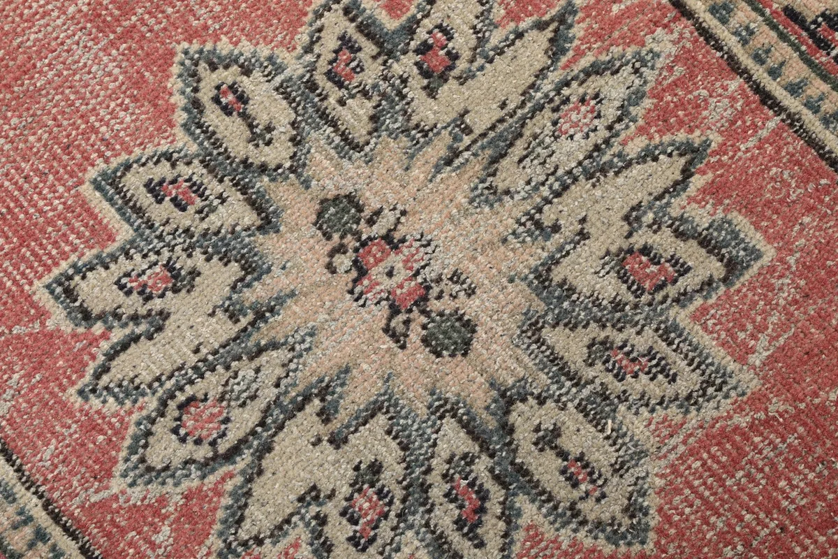 Macro detail of the hand-knotted wool pile, showcasing the intricate navy, rose, and beige colors in a medallion.