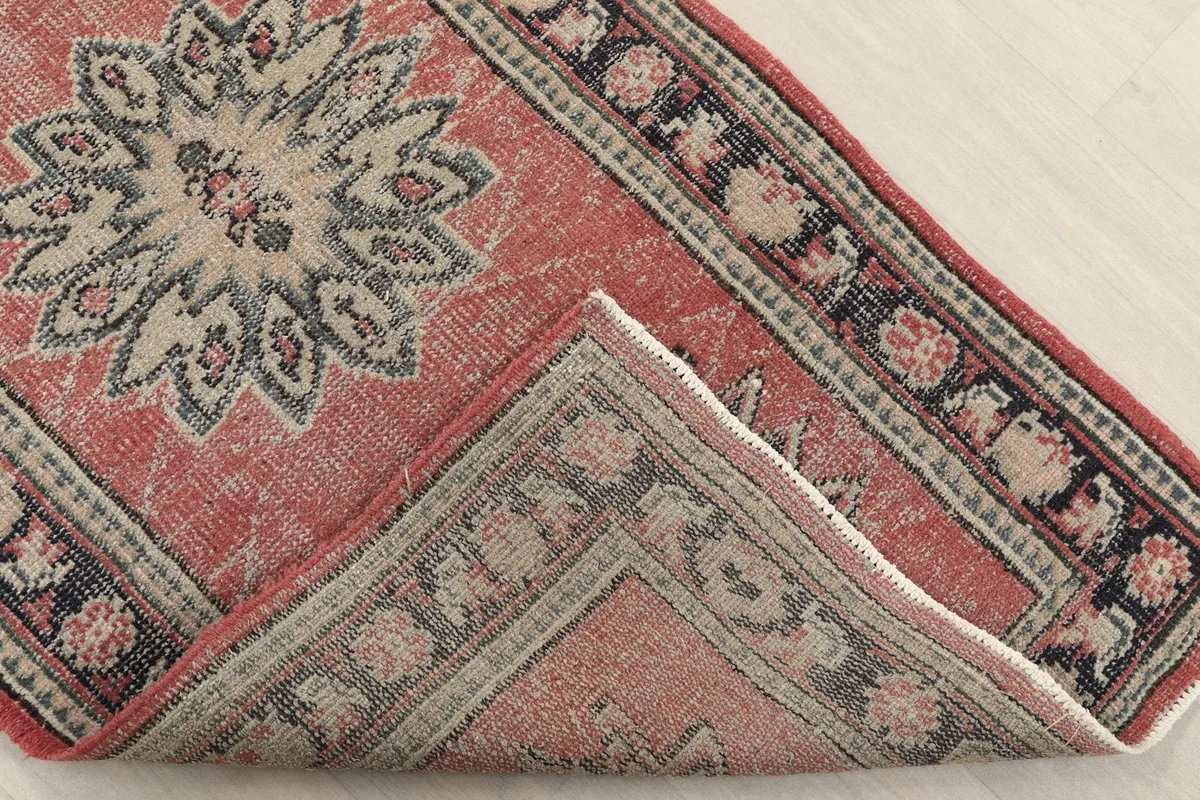 Rug corner folded back to reveal the back of the rug and the texture of the wool pile.