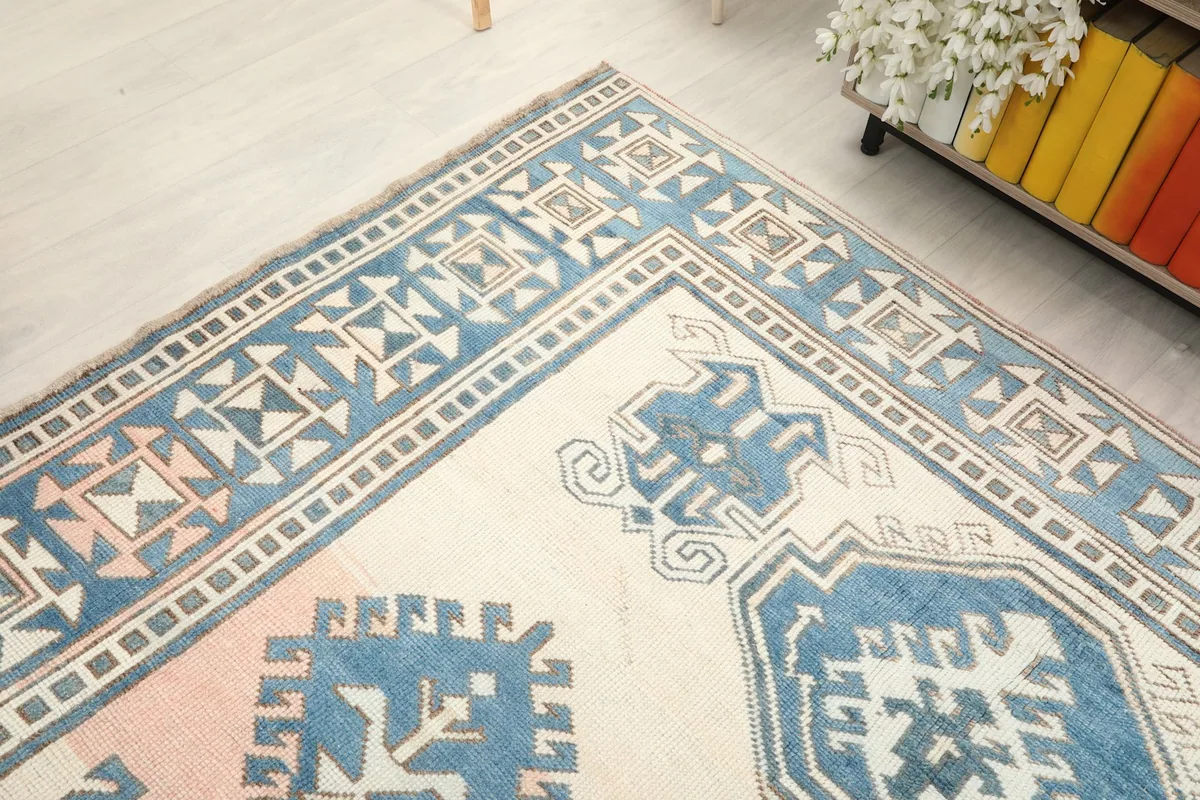 Corner view of the rug's blue border and rose field, showing texture and design