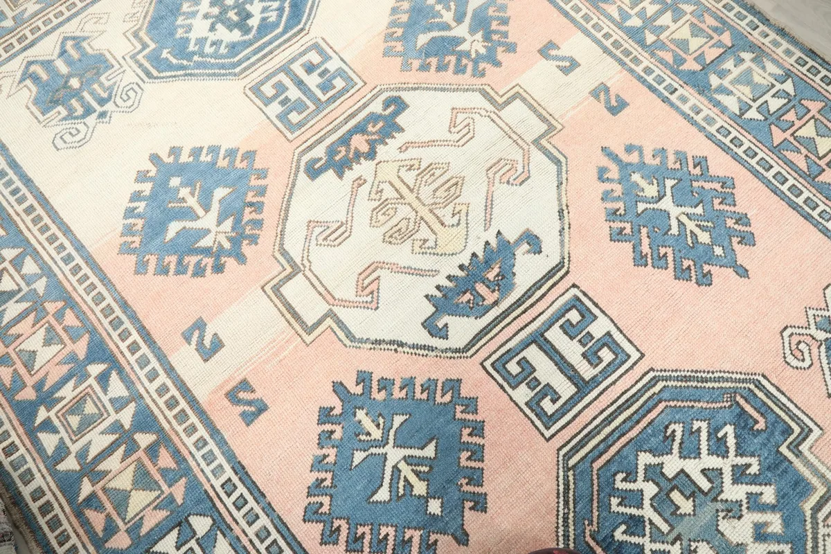 Close-up of the central rose field and blue tribal motifs on the vintage rug