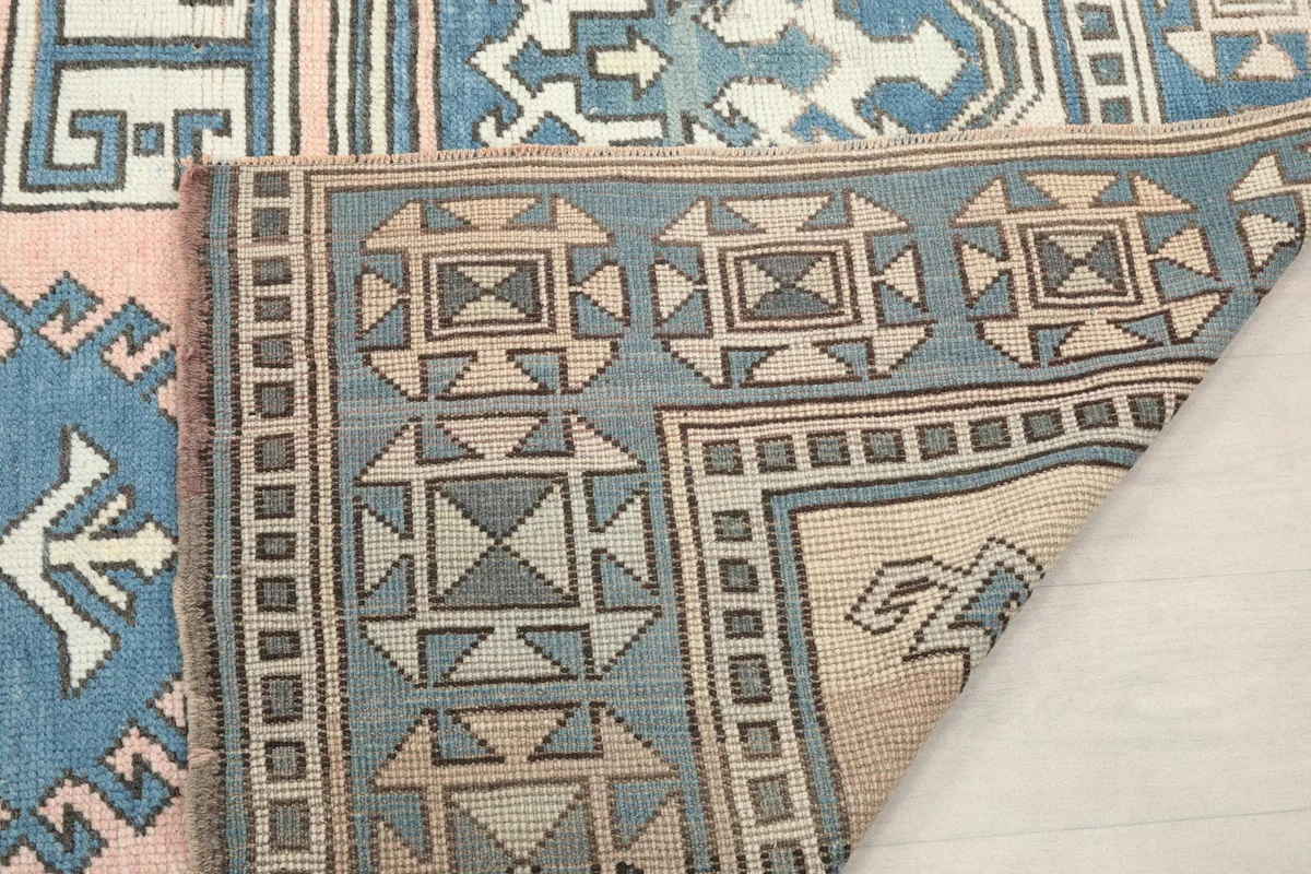 Another view of the folded rug, emphasizing the hand-knotted construction and border colors