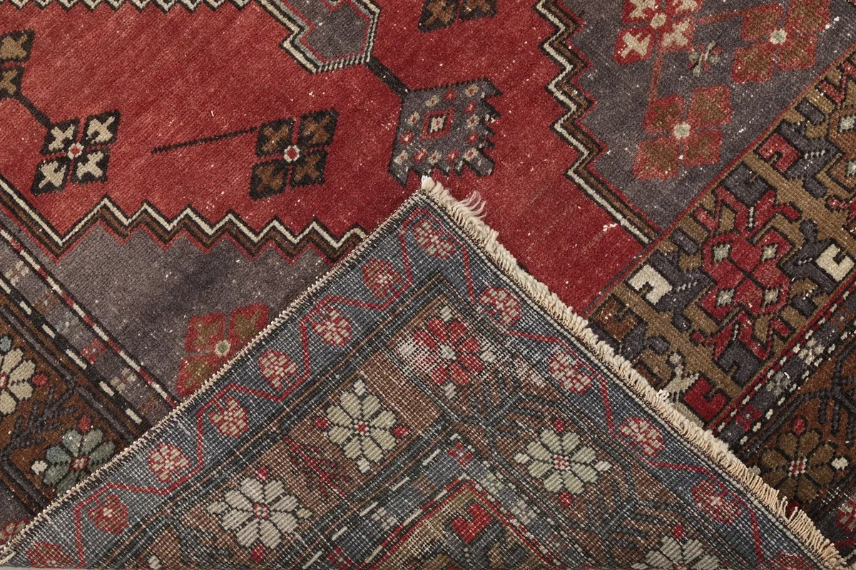 View of the rug folded to show the back and foundation alongside the pile