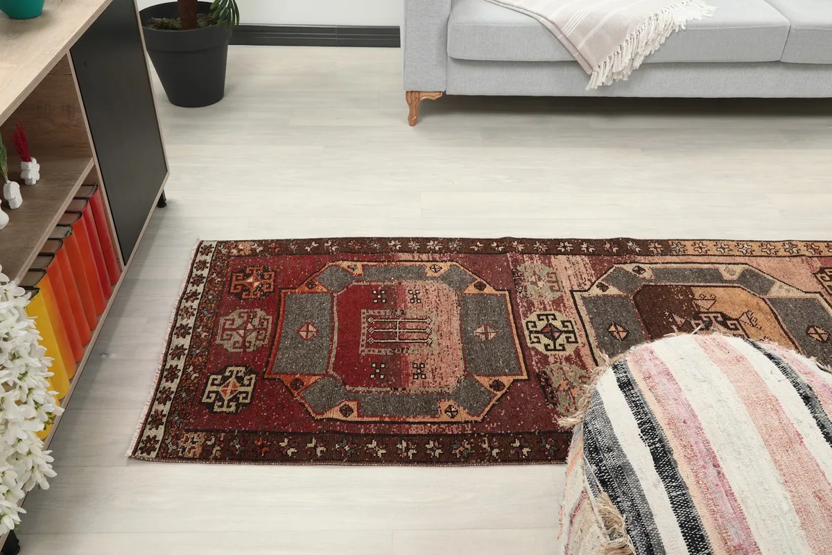 Wide shot of the runner rug extending across the floor, with a pouf and living room furniture.