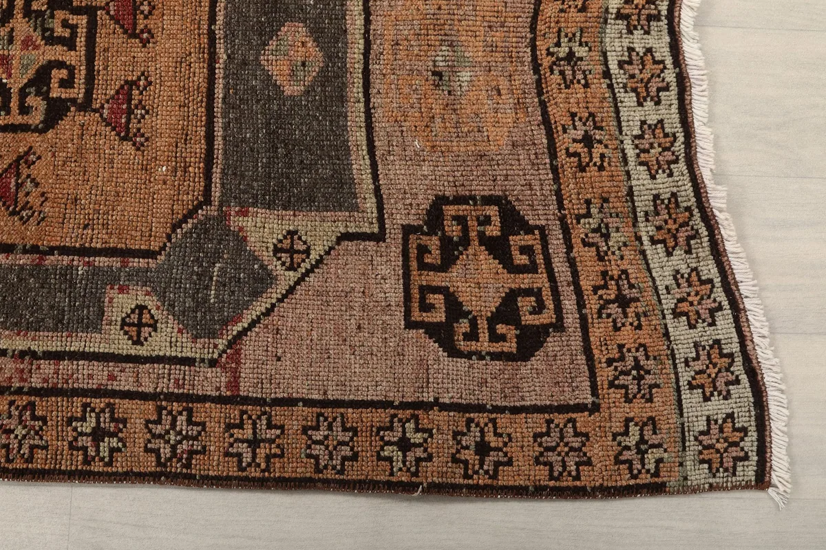 Close-up detail of the rug's border and a corner geometric motif in tan and gray.