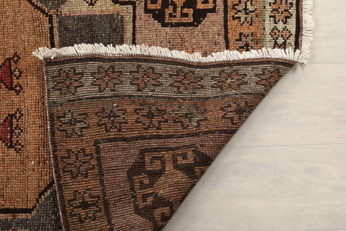 Close-up of the rug's back and fringe, indicating the hand-knotted construction and material.