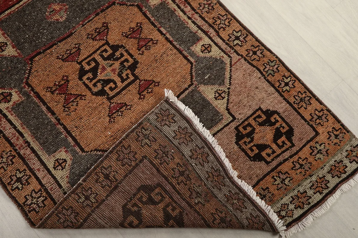 Corner of the rug folded back, showing the back of the hand-knotted cotton foundation.