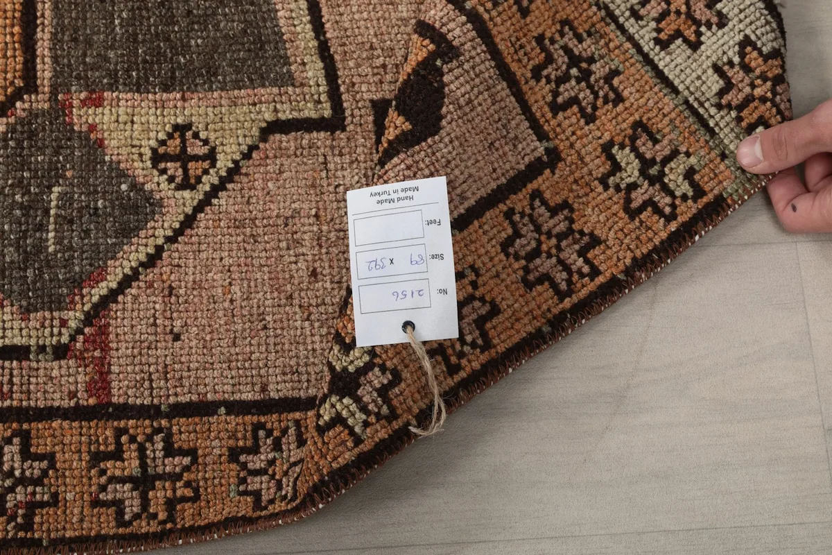 A hand holding the rug's corner with the product tag, showing the natural fringe.