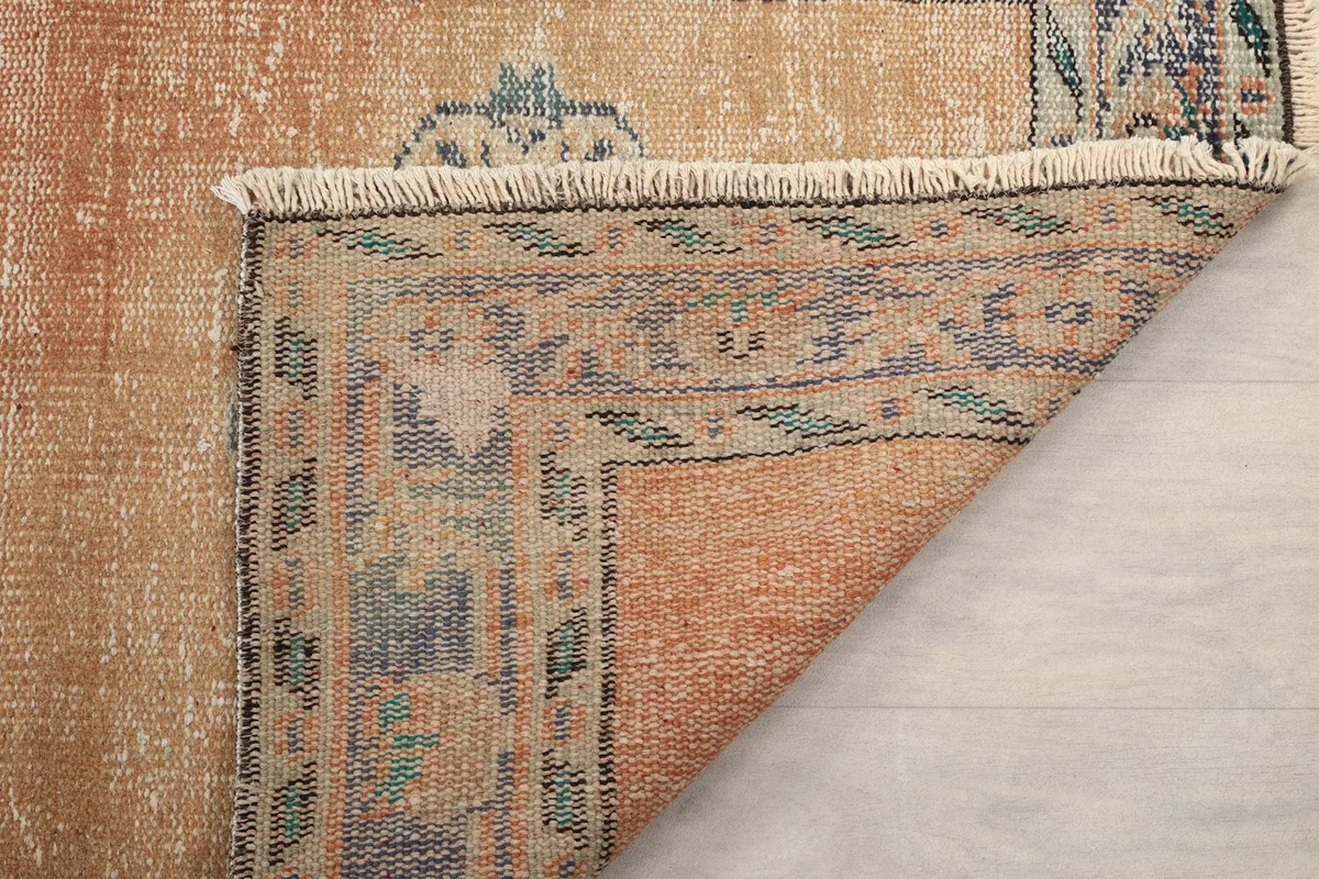 Underside view of the rug's corner, showing the tightly woven cotton foundation and short fringe.