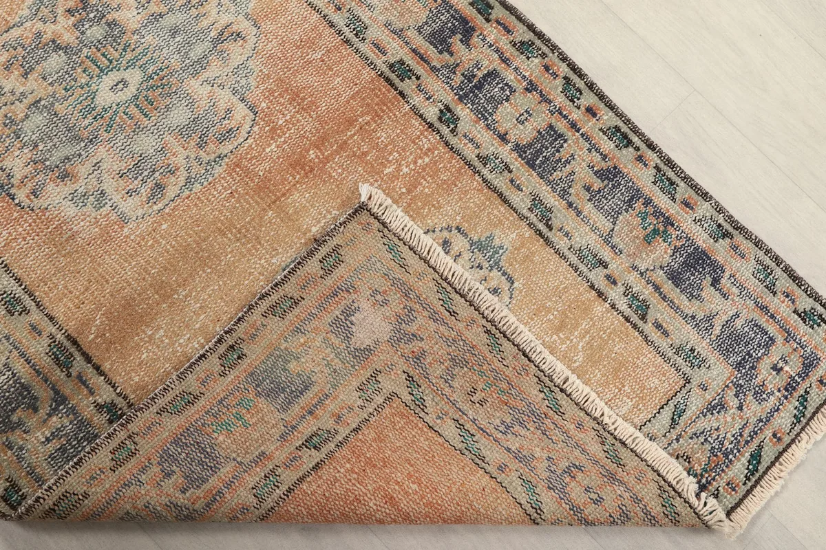 Folded corner of the rug, revealing the back of the hand-knotted cotton foundation and pile.