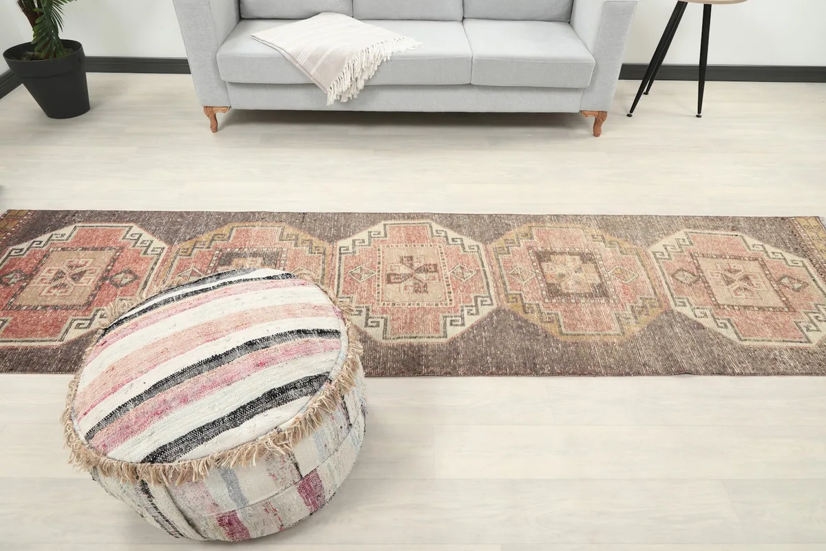 View of the runner rug in a room, extending from a sofa to an ottoman, displaying its length.