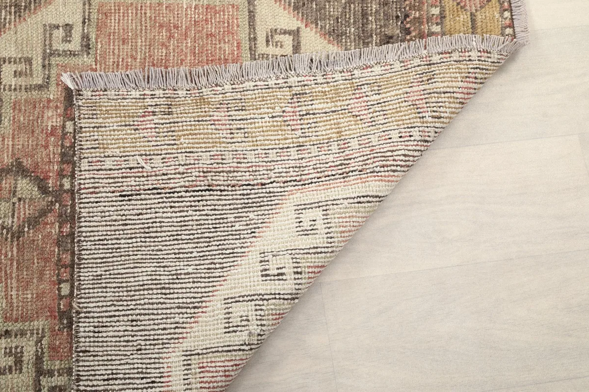 Another view of the rug's underside, showing the tightly woven cotton foundation and fringes.