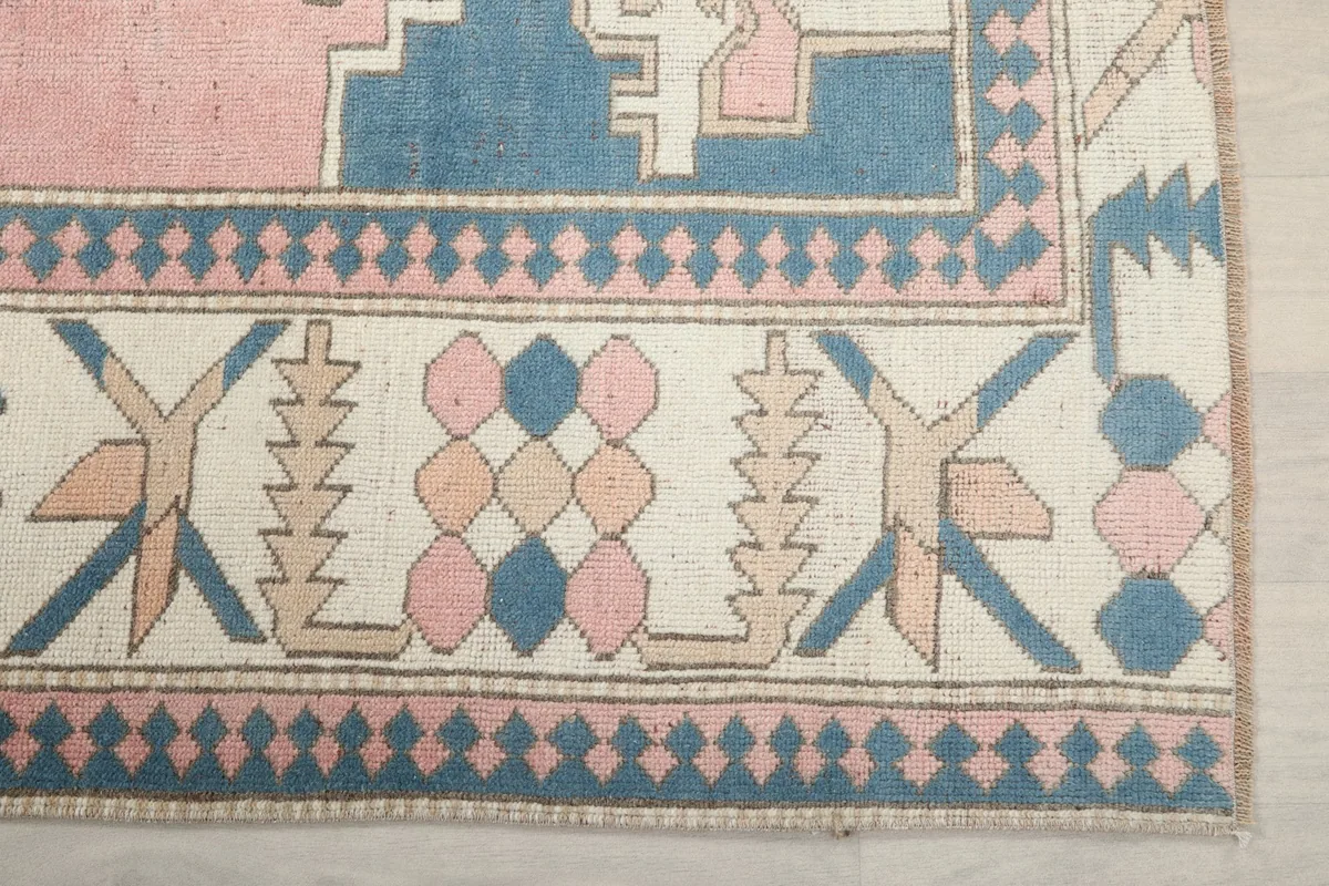Detail of the ivory border with blue and pink tribal motifs