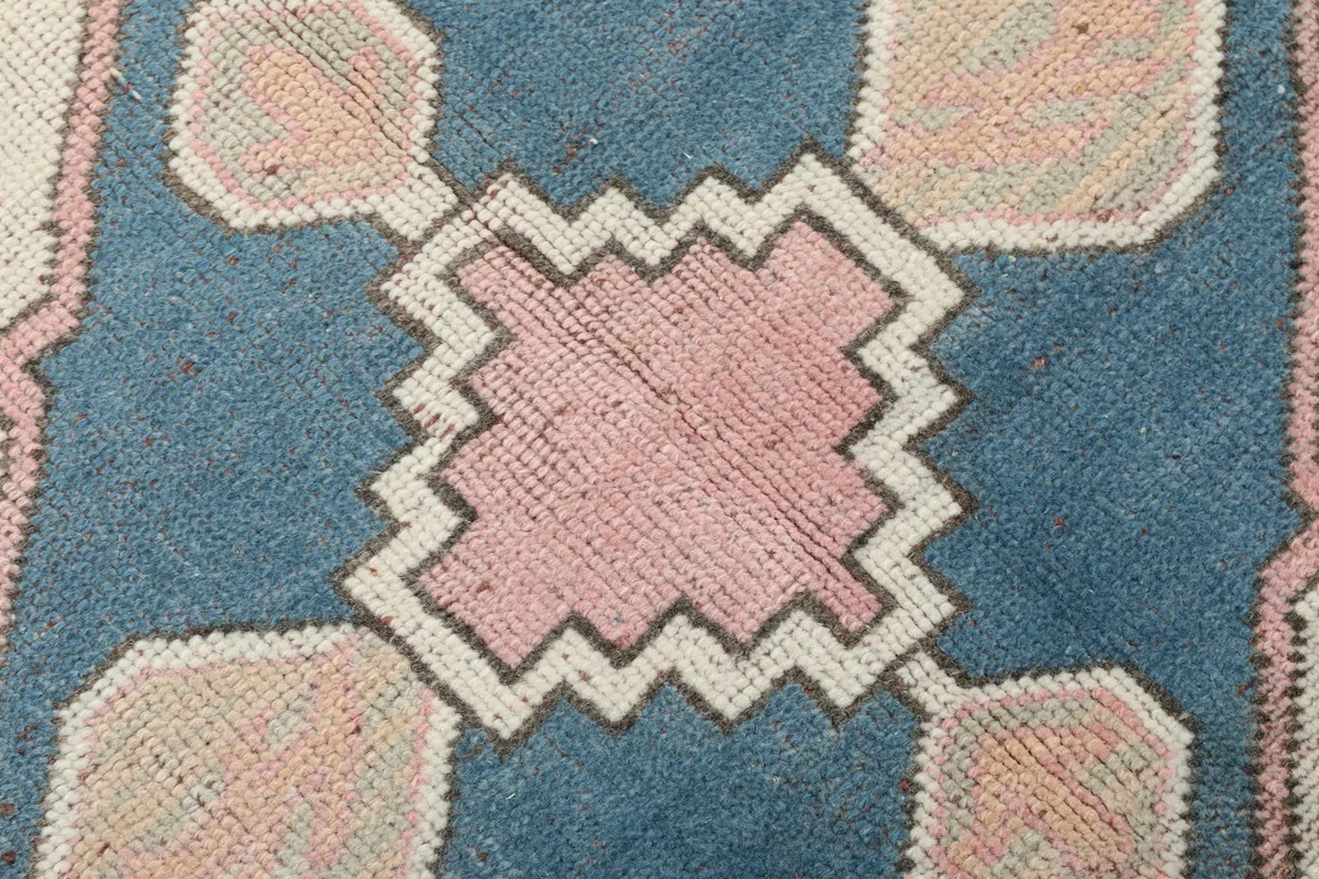 Extreme close-up showing the low pile texture and intricate knotting of the rug
