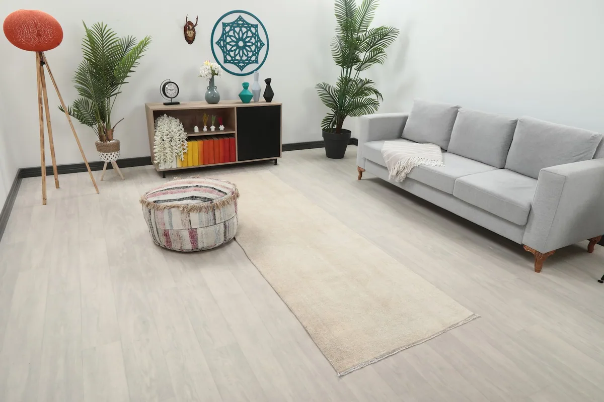 Angle view of the ivory runner rug in a room with a gray sofa and decorative items, highlighting its length.