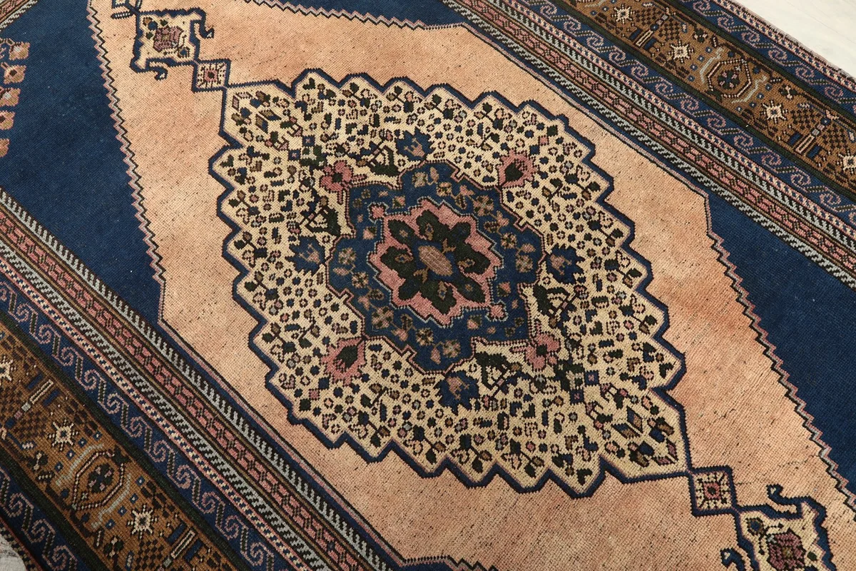 Close-up of the rug's central beige medallion with intricate navy, rose, and black motifs