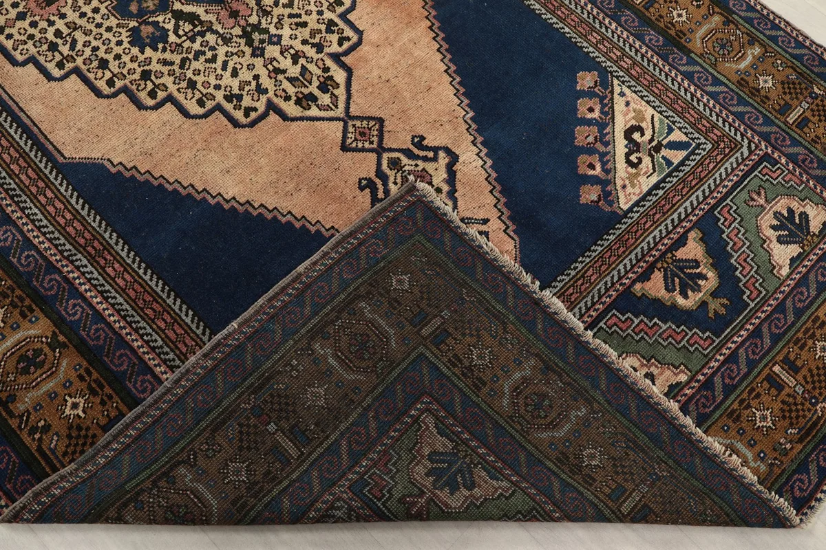 Partial view of the rug's backside and corner, revealing the hand-knotted cotton foundation
