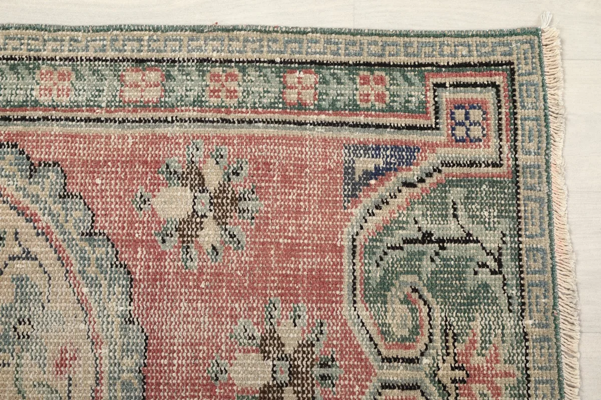 Detail of the upper right corner of the rug, showing green border and rose field