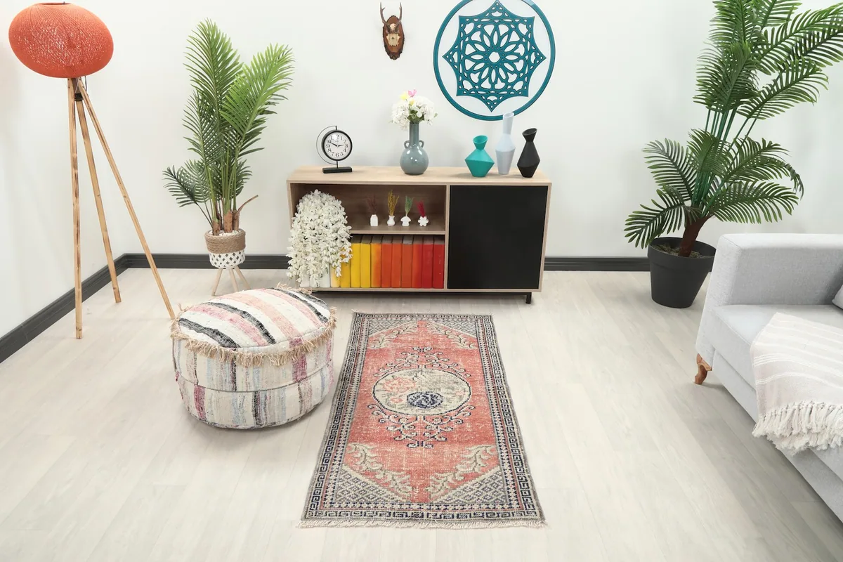 Small vintage rose and navy rug placed in a modern living space with a light-colored floor.