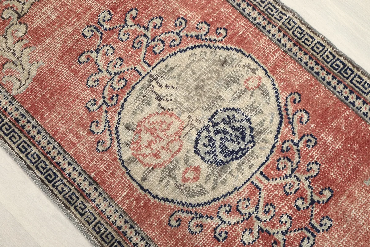 Angled close-up of the central medallion with navy and gray tones on the faded rose background.