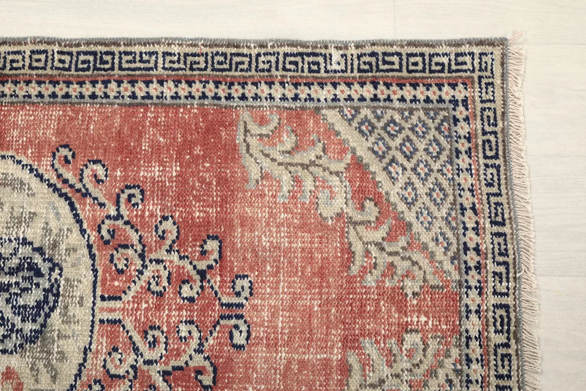 Detail of the rug's corner showing the navy geometric border and part of the rose field.