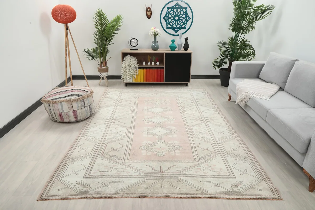 Vintage pink and beige rug in a living room setting with a gray sofa