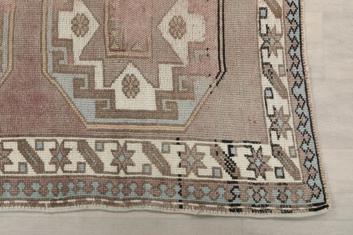 Detailed view of the rug's border design with star-like shapes and a blue stripe