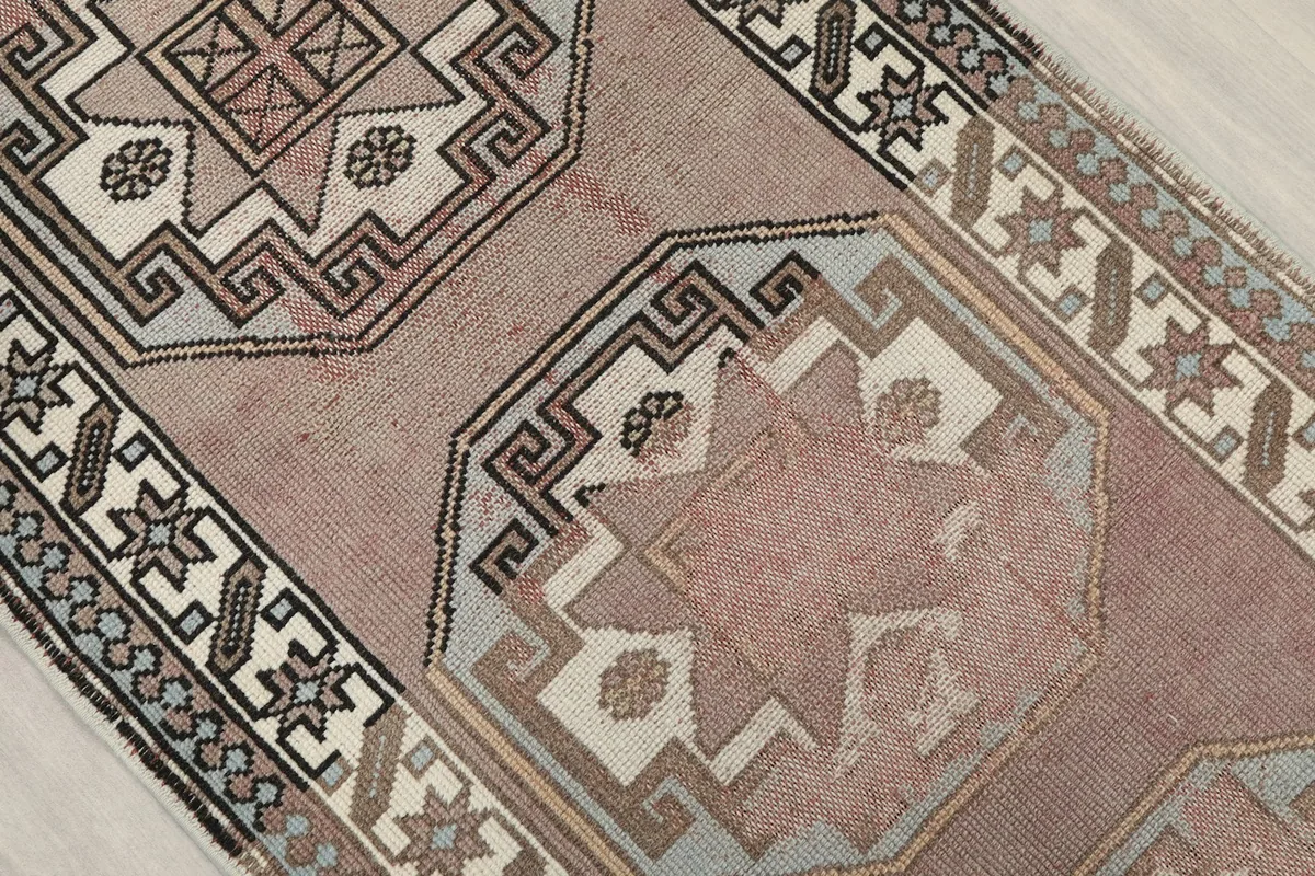Close-up of a geometric medallion showing ivory, black, and blue patterns on the rose field