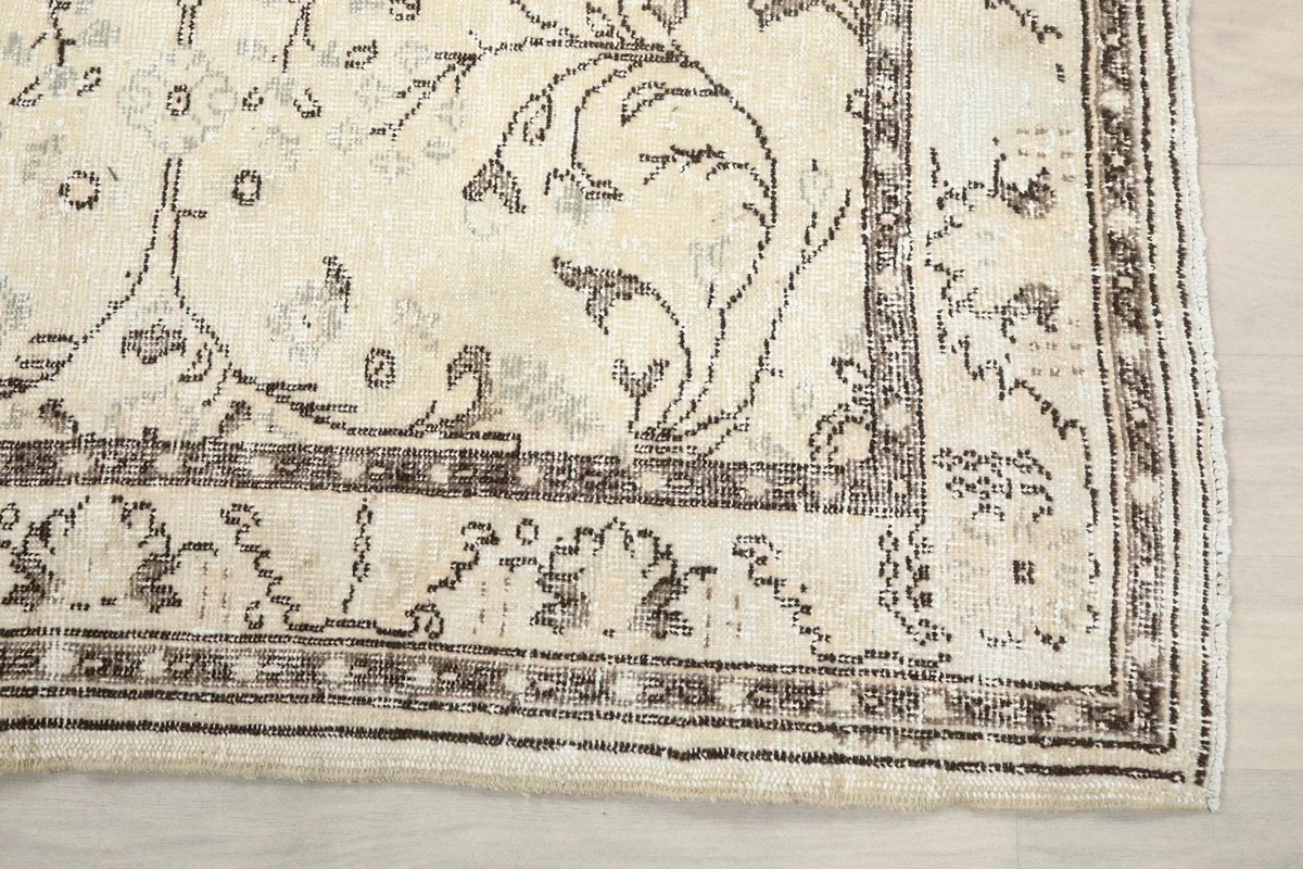 Detailed view of the corner of the ivory rug, highlighting the geometric border and floral elements