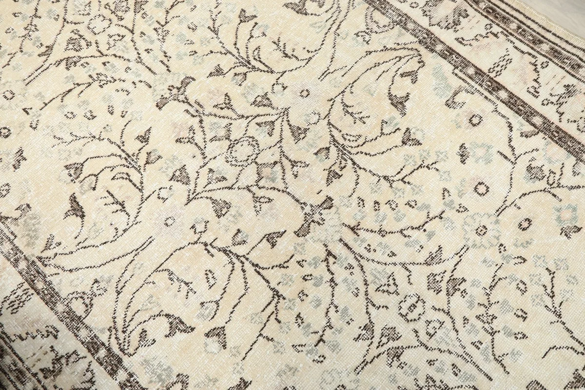 Close-up on the central floral and vine pattern of the ivory hand-knotted rug