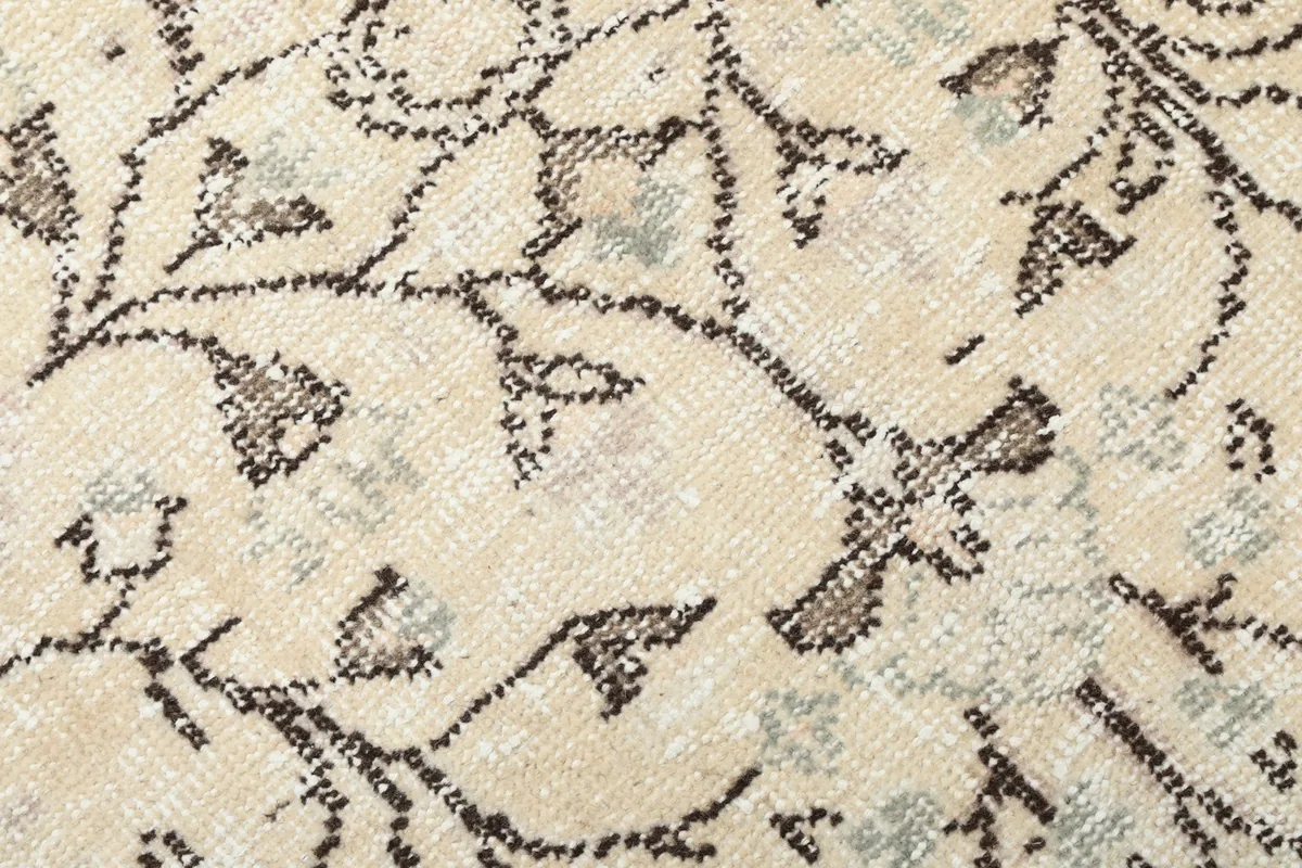 Texture and low pile of the ivory wool rug, showing subtle color variations in the brown motifs