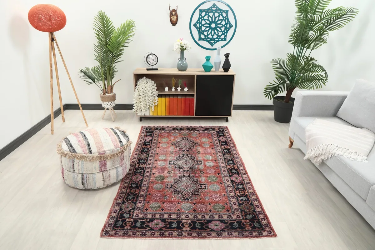 Vintage rust rug displayed in a bright living room setup with a gray sofa and light wood flooring.