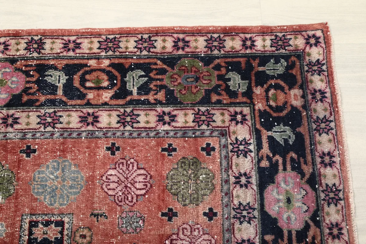 Detail of the rug's corner, highlighting the intricate navy border with floral and geometric motifs.