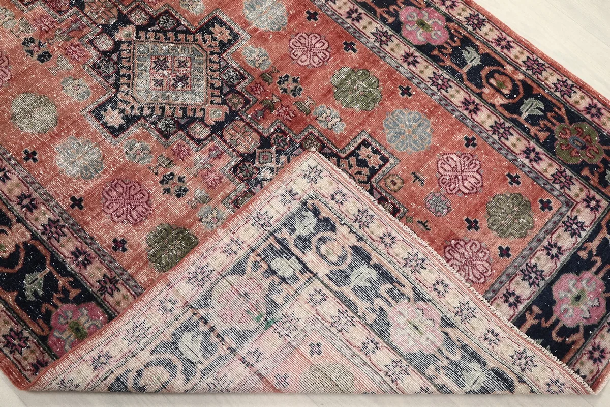 Folded corner of the rug revealing the cotton foundation and the reverse side of the hand-knotted wool pile.
