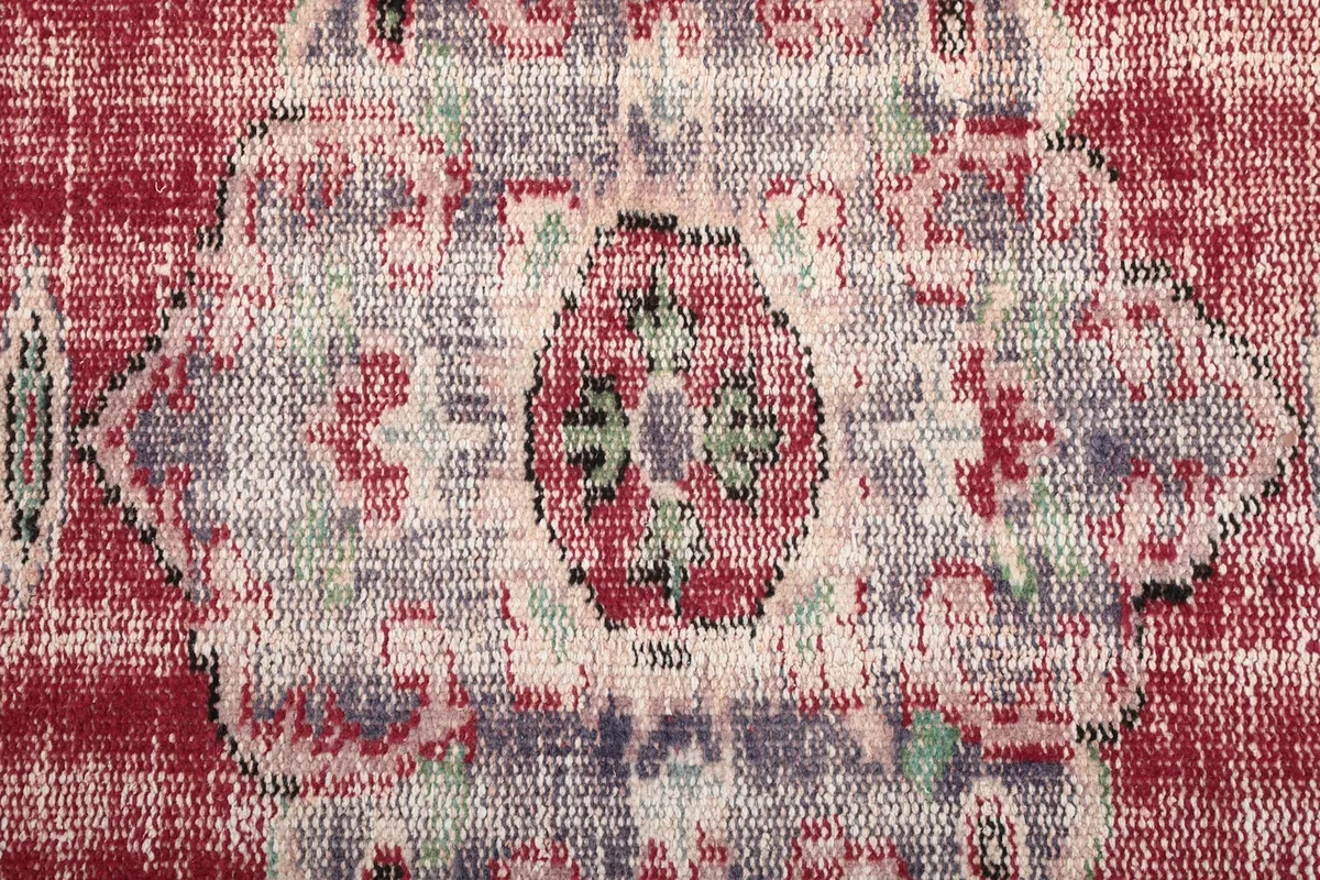 Macro detail of the central medallion's intricate design and faded colors in rose, blue, and green.