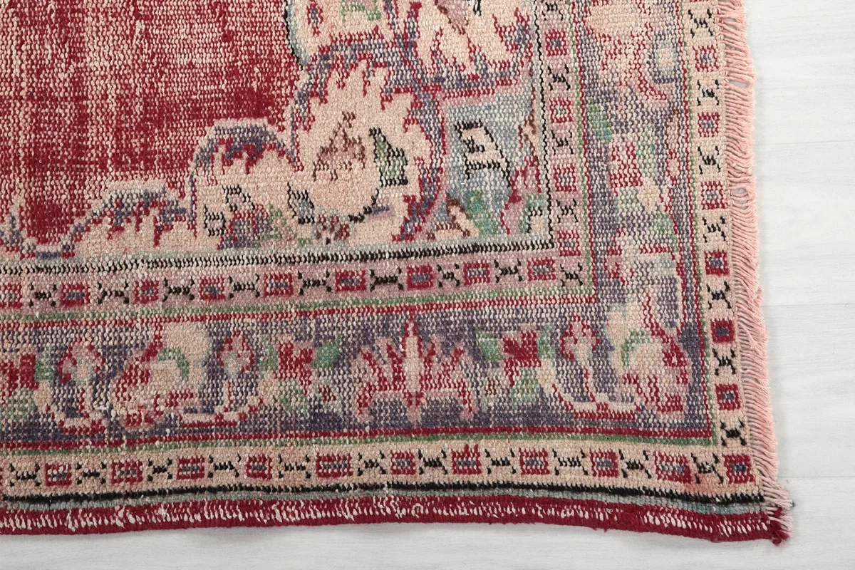 Detail of the rug's border pattern in blue, ivory, and green, showing hand-knotted texture.
