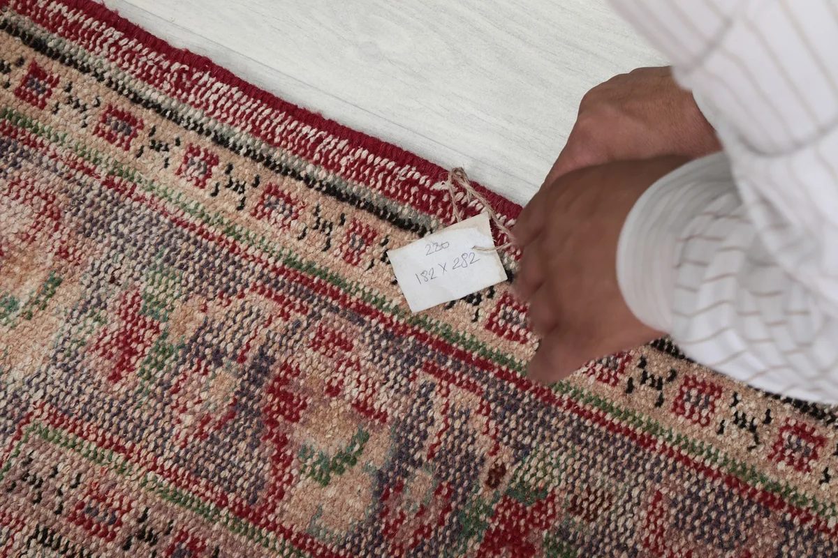 Detail of the rug's reverse side, showing the hand-knotted construction and a small tag.