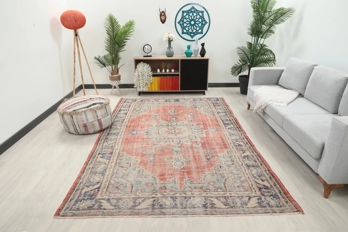 Vintage rose and blue rug displayed in a modern living room setting with a gray sofa.