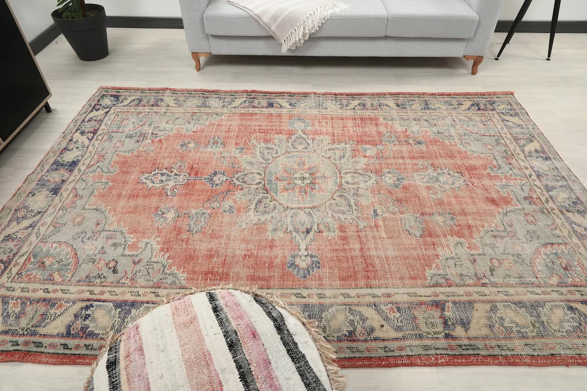 Full view of the rose and blue vintage rug in the living room, centered with a pouf.