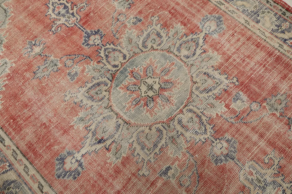 Close-up of the central medallion and surrounding rose field, showing faded colors and texture.