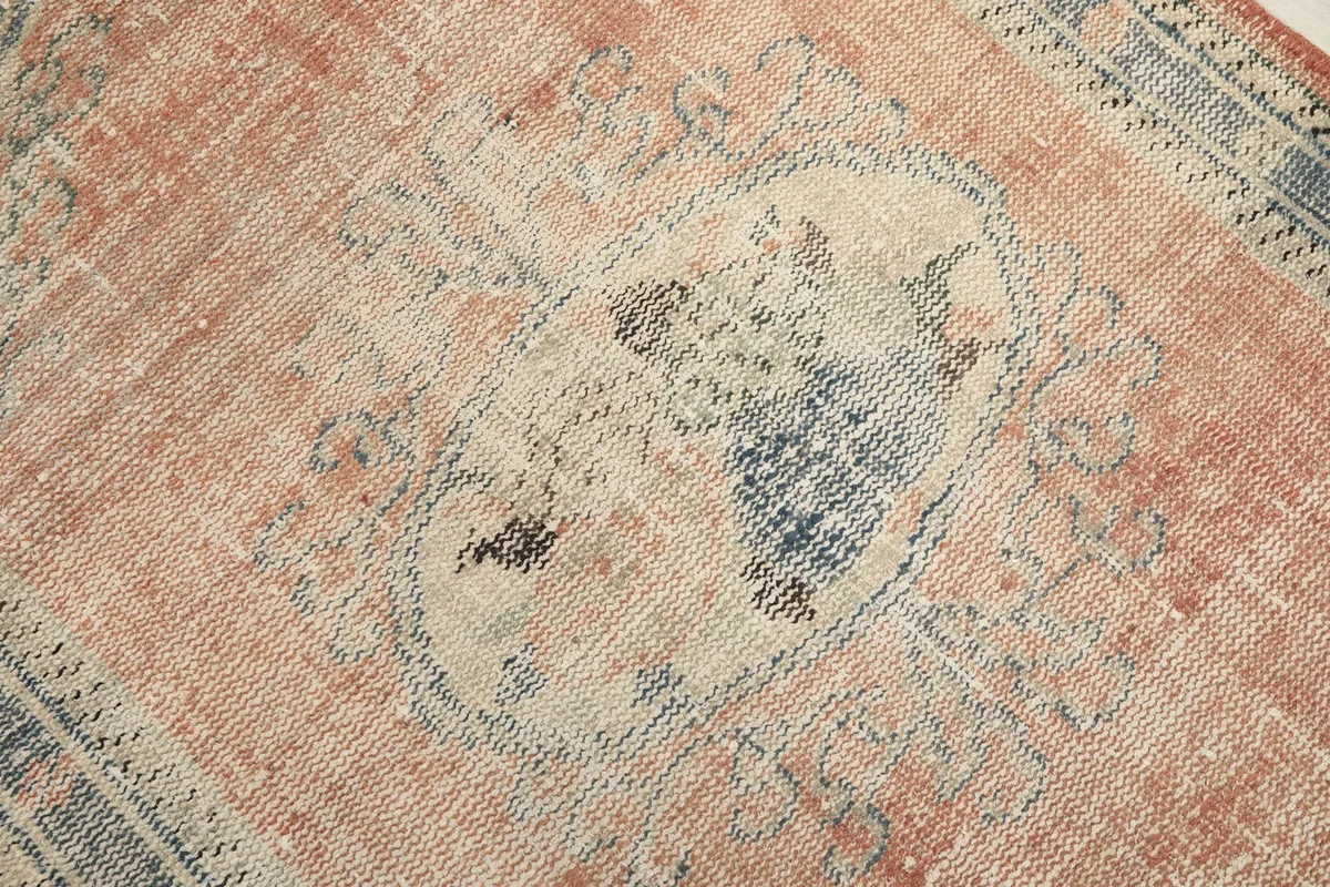 Close-up of the central blue and ivory medallion motif on the faded rust background